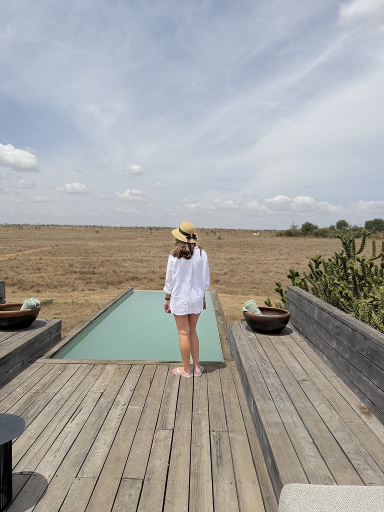 Woman walking toward an infinity pool overlooking the savanna at a luxury safari lodge in Kenya