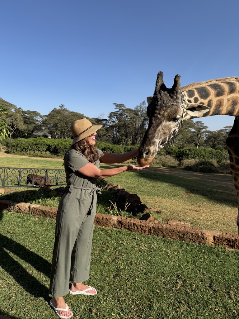 Traveler feeding a giraffe at Giraffe Manor in Nairobi, Kenya, a unique luxury safari experience with up-close wildlife encounters
